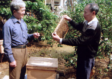 Ông Phan Quốc Huy (bên phải) đang giới thiệu kinh nghiệm nuôi ong mật.
