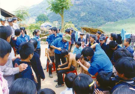 Thanh niên tình nguyện cắt tóc gội đầu cho trẻ em xã vùng cao Văn Chấn. (Ánh: Đặng Phương Lan)