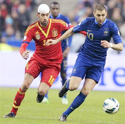 Tiền đạo Karim Benzema (phải, tuyển Pháp) nỗ lực đi bóng trước Sergio Busquets của Tây Ban Nha.