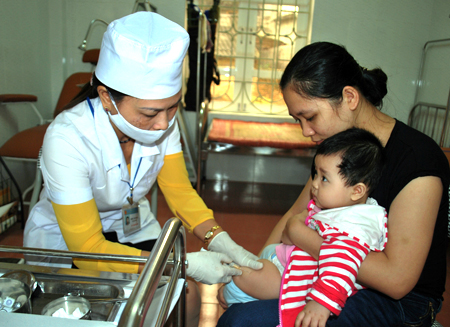 Cán bộ y tế phường Nguyễn Thái Học (thành phố Yên Bái) tiêm phòng cho trẻ.