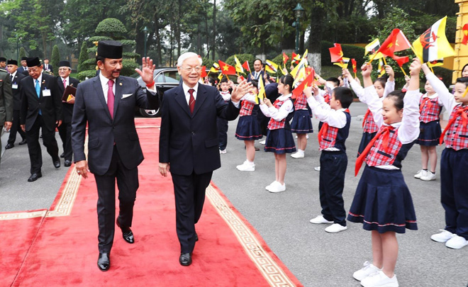 Tổng Bí thư, Chủ tịch nước Nguyễn Phú Trọng và Quốc vương Brunei Hassanal Bolkiah vẫy chào thiếu nhi Việt Nam tại lễ đón.