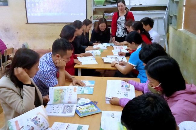 Teachers at Phuc Son primary school in Nghia Lo town, Yen Bai province, study sample textbooks.