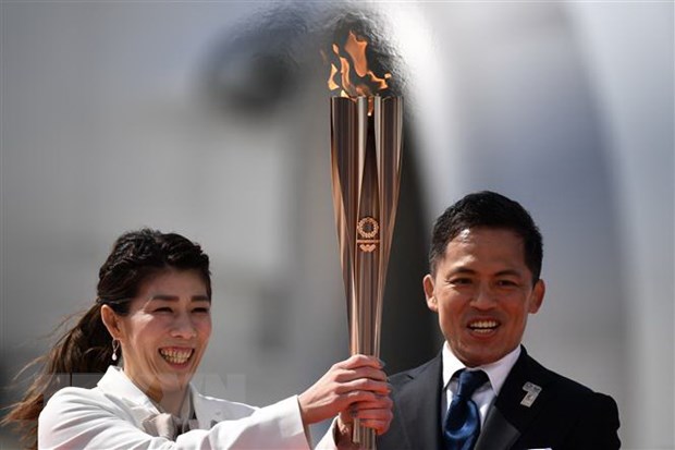 Vận động viên Nhật Bản ba lần giành Huy chương Vàng Olympic Saori Yoshida (trái) và Tadahiro Nomura (phải) giơ cao ngọn đuốc Olympic Tokyo 2020 sau khi đuốc được chuyển về từ Hy Lạp, tại căn cứ không quân Matsushima ở Higashimatsushima, tỉnh Miyagi ngày 20/3/2020.