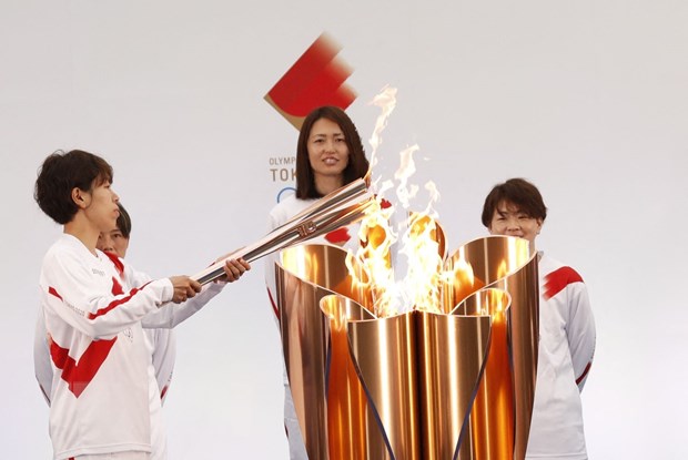 Vận động viên bóng đá Nhật Bản Azusa Iwashimizu (trái) thắp sáng ngọn đuốc Olympic tại lễ rước đuốc Olympic Tokyo 2020, ở Naraha, tỉnh Fukushima, Nhật Bản, ngày 25/3/2021.