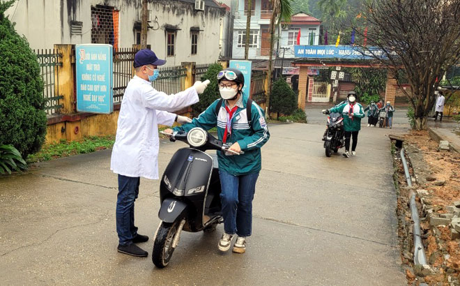 Học sinh Trường THCS Quang Trung, phường Đồng Tâm, thành phố Yên Bái được kiểm tra thân nhiệt trước khi vào lớp trong ngày đầu tiên trở lại trường 15/3. Ảnh: Minh Huyền