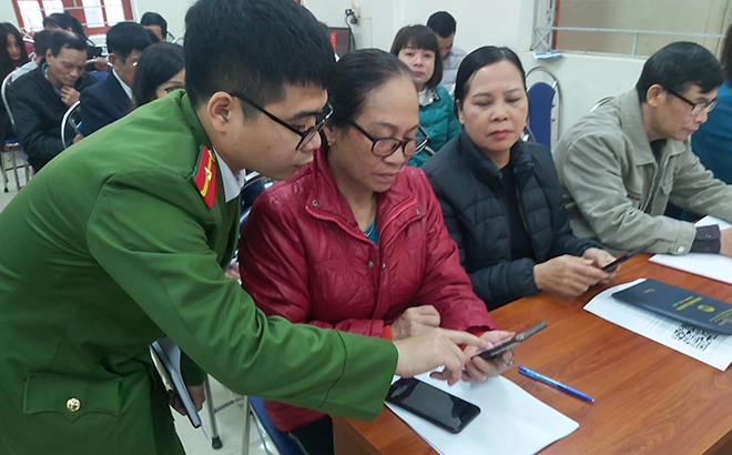 Cán bộ Công an phường Yên Thịnh, thành phố Yên Bái hỗ trợ hướng dẫn người dân cài đặt ứng dụng tiện ích trên điện thoại thông minh.