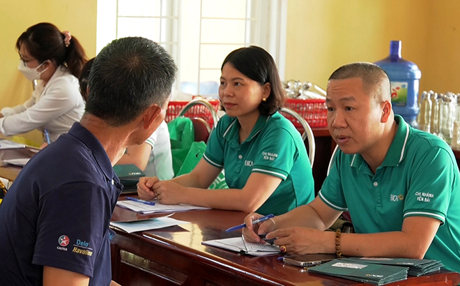 Cán bộ Ngân hàng BIDV Yên Bái tư vấn người dân xã Minh Bảo, thành phố Yên Bái sử dụng các tiện ích thanh toán không dùng tiền mặt.