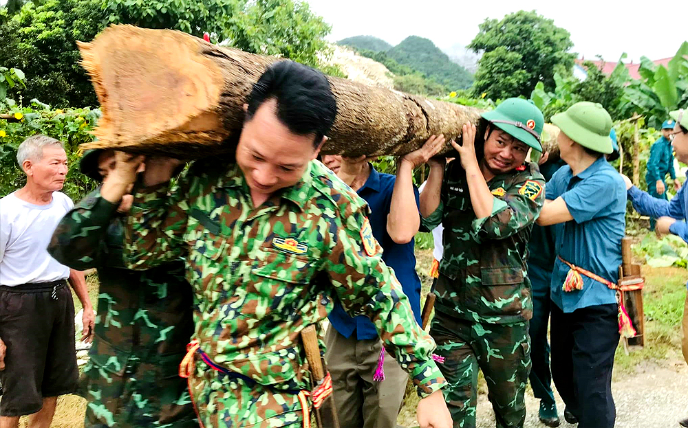 Cán bộ, chiến sỹ lực lượng vũ trang huyện tham gia vận động nhân dân chặt cây, hiến đất làm đường giao thông nông thôn.