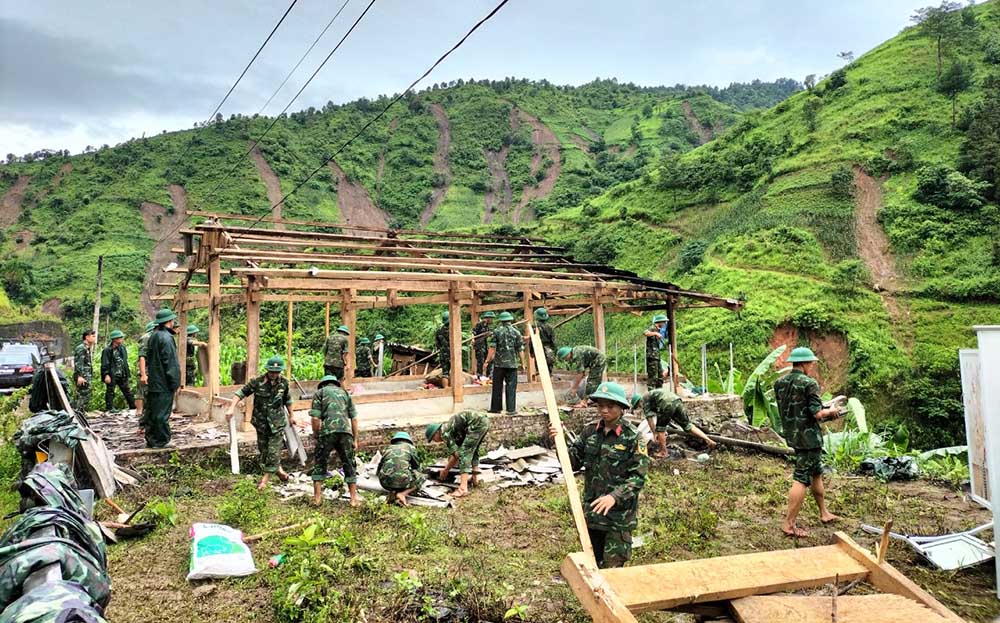 Cán bộ, chiến sĩ lực lượng vũ trang huyện Mù Cang Chải giúp hộ khó khăn ở xã Hồ Bốn làm nhà, thực hiện mục tiêu xóa đói, giảm nghèo của địa phương.