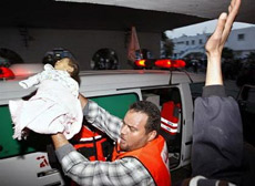 Nhân viên y tế bế một bé gái Palestine sau khi tên lửa của Israel rơi xuống một căn nhà ở Dải Gaza ngày 1-3