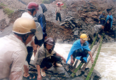 Ông Hờ Bùa Tu - Chủ tịch xã Tà Xi Láng, huyện Trạm Tấu (ngồi giữa) đang chỉ đạo đội cứu hộ, cứu nạn tập kết vật liệu làm cầu tạm cho dân đi lại.
