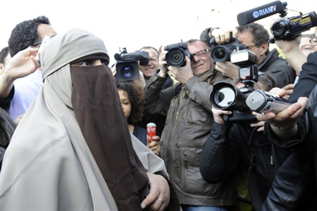 Các nhà báo vây quanh một phụ nữ đeo mạng che mặt tham gia cuộc biểu tình trước nhà thờ Notre Dame tại Paris để phản đối luật cấm đeo mạng che mặt tại nơi công cộng.