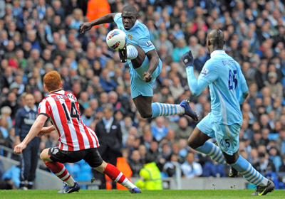 Hậu vệ Micah Richards (giữa) của Man.City chặn đường bóng đến tiền vệ Jack Colback của Sunderland (áo đỏ).