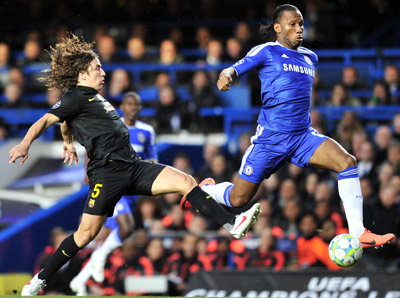 Tiền đạo Didier Drogba vượt qua hậu vệ Carles Puyol của Barcelona.