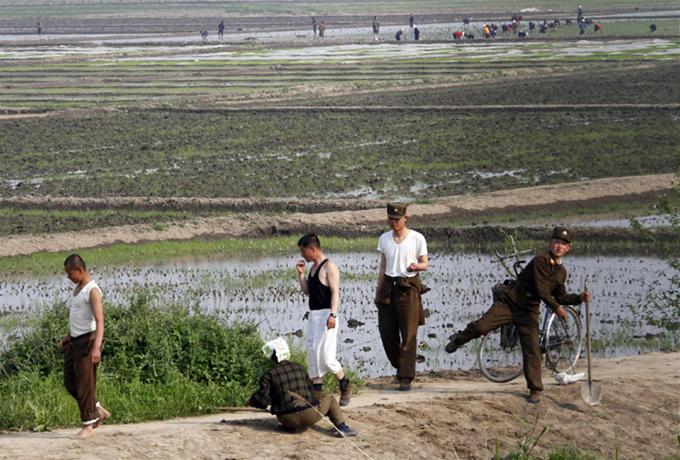 Một binh sĩ Triều Tiên (bìa phải) ném đá về phía một tàu du lịch Trung Quốc đậu tại bờ sông Áp Lục ở thành phố Sinuiju của Triều Tiên, khu vực nằm đối diện với thành phố biên giới Đan Đông của Trung Quốc