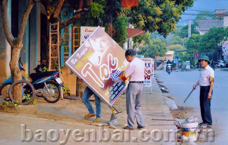 Các thành viên của đội tự quản thị trấn Nông trường Nghĩa Lộ nhắc nhở, tuyên truyền người dân không để biển quảng cáo lấn chiếm hành lang, vỉa hè.
