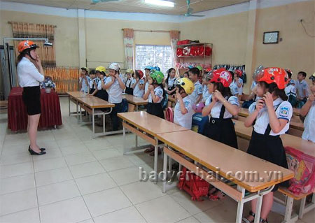 Giáo viên Trường Tiểu học Nguyễn Trãi (thành phố Yên Bái) hướng dẫn học sinh đội mũ bảo hiểm.