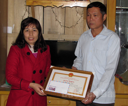 Cán bộ Ban Dân vận huyện Trấn Yên trao bằng khen của Ban Dân vận Trung ương cho ông Dương Kim Trọng.

