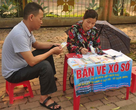 Một bàn đại lý bán vé XSKT Yên Bái tại phường Đồng Tâm thành phố Yên Bái ghi vé số cho khách hàng.