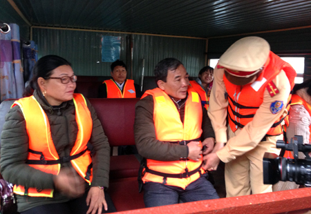 Lực lượng cảnh sát giao thông hướng dẫn người dân mặc áo phao khi đi tàu khách tại bến cảng Hương Lý, thị trấn Yên Bình, huyện Yên Bình.
