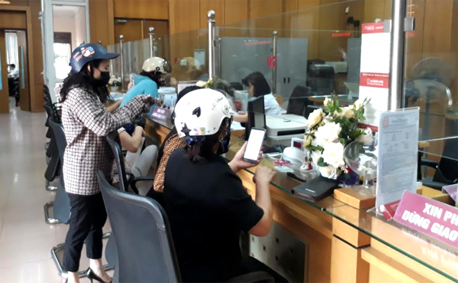 Nhiều khách hàng vào các phòng giao dịch ngân hàng vẫn đội mũ bảo hiểm, đeo khẩu trang và mặc áo chống nắng.