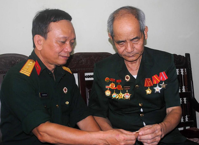 Cựu chiến binh Đỗ Quang Bình (bên phải) ôn lại những kỷ vật của đời lính.