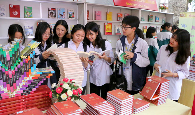 School students visit and read book at exhibition booths.
