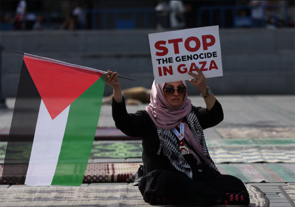 Một người phụ nữ cầm cờ Palestine và biểu ngữ với nội dung ủng hộ người Palestine ở Gaza tại thành phố Istanbul, Thổ Nhĩ Kỳ vào tháng 10-2023