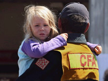 Thành viên đội cứu hỏa bồng con gái chạy nạn khi lửa tàn phá thị trấn Kinglake, phía đông bắc Melbourne.