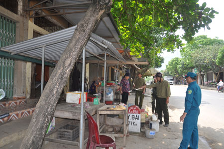 Lực lượng công an và dân quân thị trấn Nông trường Nghĩa Lộ nhắc nhở các hộ kinh doanh không lấn chiếm, vi phạm hành lang an toàn giao thông.