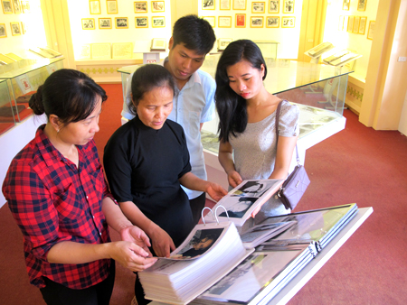 Cô Chu Thị Tú Liên (giữa) và các bạn trẻ xem tập san “Chủ tịch Hồ Chí Minh với sự nghiệp giáo dục” được trưng bày tại Khu tưởng niệm Chủ tịch Hồ Chí Minh thị xã Nghĩa Lộ.