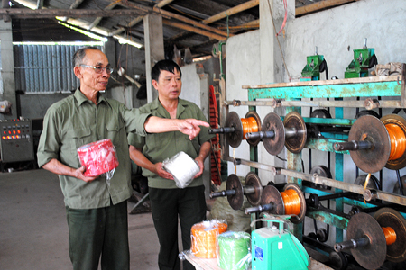Cựu chiến binh Nguyễn Hùng Cường (bên trái)  giới thiệu hệ thống máy cuộn dây khâu, dây buộc.
