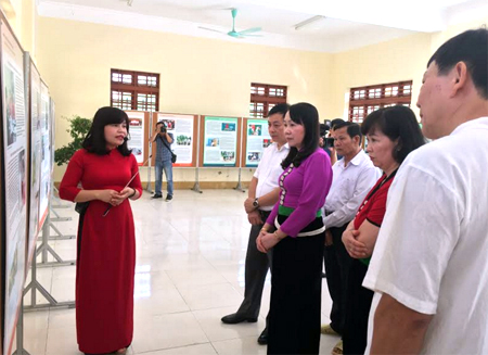 Các đại biểu thăm quan triển lãm ảnh và nghe hướng dẫn viên Bảo tàng Hồ Chí Minh giới thiệu về triển lãm.