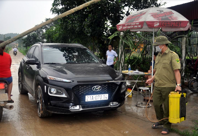 Lực lượng chức năng phun khử trùng các phương tiện giao thông ra, vào thôn Liên Hiệp, huyện Trấn Yên.