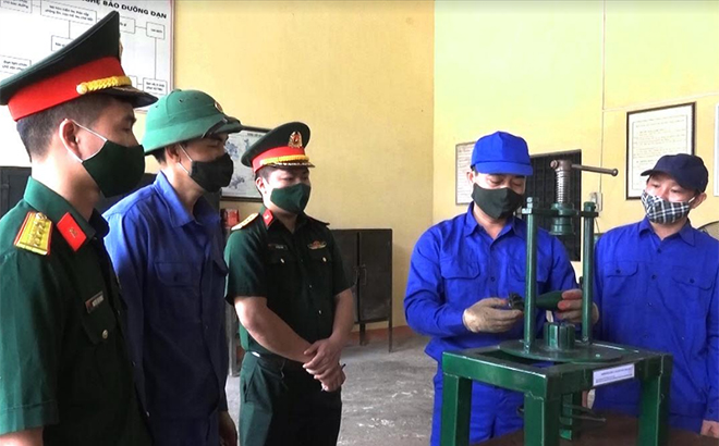 Đại úy quân nhân chuyên nghiệp Phùng Văn Tiến (thứ 2, phải sang) giới thiệu và thực hành nắn chỉnh cánh đuôi đạn cối 60.