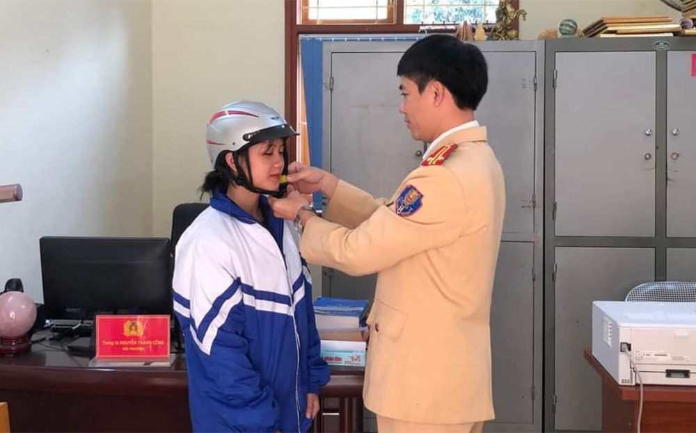 Cán bộ cảnh sát giao thông thị xã Nghĩa Lộ hướng dẫn đội mũ bảo hiểm đúng cách cho học sinh Trường Phổ thông Dân tộc nội trú THPT Miền Tây.