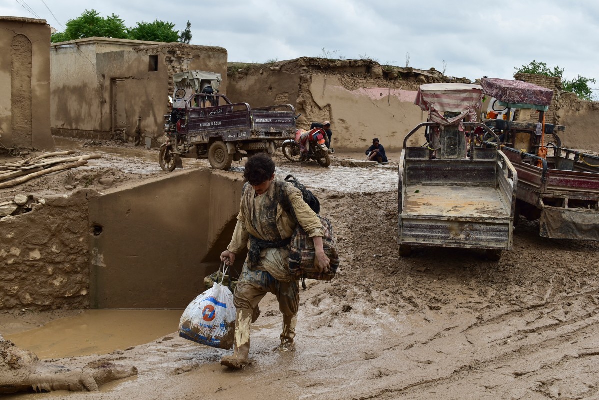 Người đàn ông Afghanistan mang đồ đạc đi qua con đường đầy bùn sau trận lũ quét ở làng Laqiha, huyện Baghlan-i-Markazi, tỉnh Baghlan, ngày 11/5.