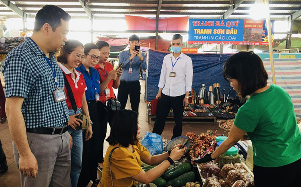 Người dân thực hiện thanh toán không dùng tiền mặt tại chợ Bến Đò, thành phố Yên Bái.