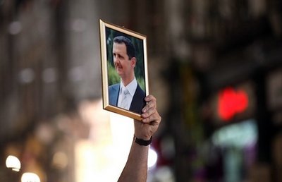 Một người Syria cầm ảnh của Tổng thống Bashar al-Assad trong cuộc tuần hành ủng hộ chính phủ ở Damascus hồi tháng 4.