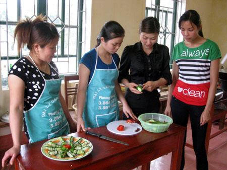 Giáo viên trường Cao đẳng Công nghệ Kinh tế Hà Nội hướng dẫn học viên lớp dạy nghề nấu ăn xã Phúc Lộc cách tỉa hoa từ rau, củ, quả.
