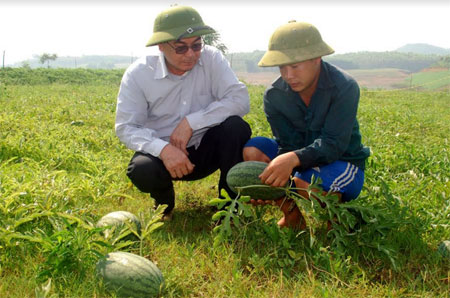 Ông Hoàng Phượng Vỹ - Chủ tịch UBND xã Xuân Lai (bên trái) trao đổi với người dân trồng dưa hấu trên đất bán ngập.
