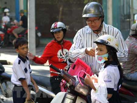Phụ huynh đội mũ bảo hiểm cho trẻ khi tham gia giao thông.