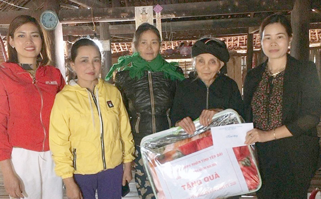 Trieu Thi Minh Hien (right) presents pre-Tet gift packages to impoverished households on the behalf of the provincial businesswomen’s association this year.