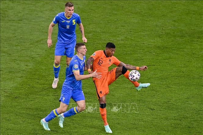 Pha tranh bóng quyết liệt giữa hậu vệ Hà Lan Patrick van Aanholt (phải) và các cầu thủ Ukraine trong trận đấu vòng chung kết EURO 2020 trên sân ở Amsterdam, ngày 13/6/2021.