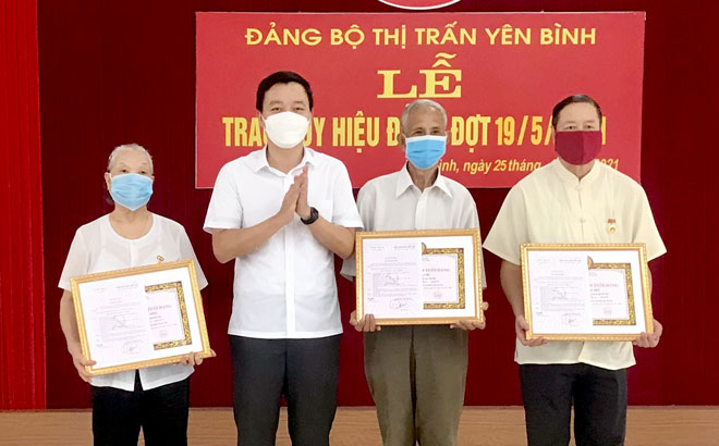 Bí thư Huyện ủy Yên Bình An Hoàng Linh trao Huy hiệu Đảng cho các đảng viên tại Đảng bộ thị trấn Yên Bình.