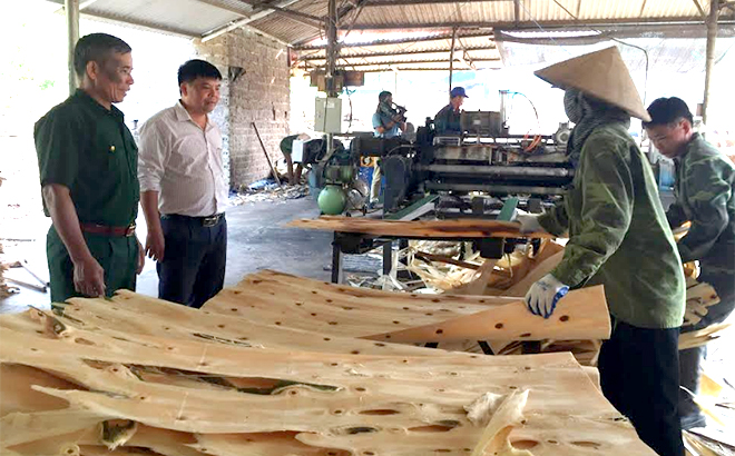 Cựu chiến binh Nguyễn Đức Khang (ngoài cùng bên trái) giới thiệu xưởng chế biến gỗ của gia đình.