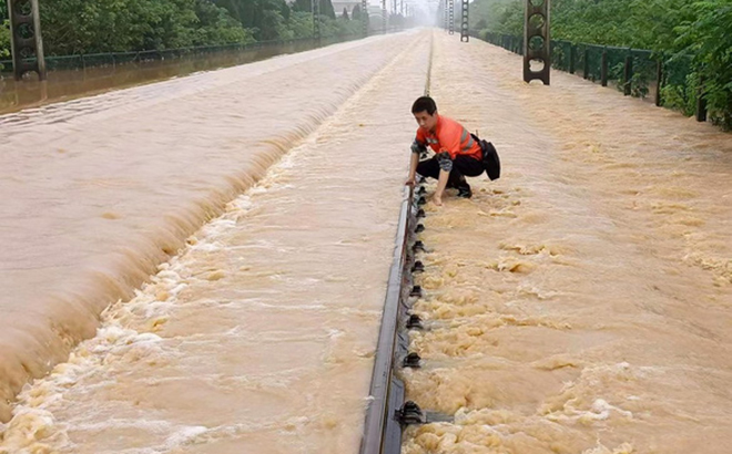 Nhân viên đường sắt kiểm tra đường ray bị ngập sau mưa lớn ở thành phố Thượng Nhiêu, tỉnh Giang Tây, Trung Quốc vào ngày 21-6.