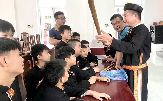 Nghệ Nhân ưu tú Hoàng Hữu Định giới thiệu với các em học sinh kỹ thuật thổi sáo nứa.