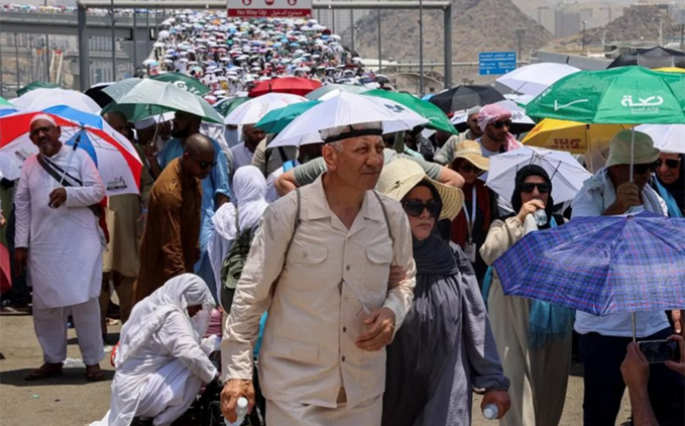 Những người hành hương Hồi giáo cầm ô đi bộ dưới nắng nóng, trong dịp lễ Hajj ở Ả Rập Xê-út, ngày 17/6.