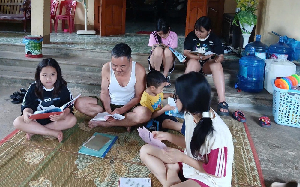 Ông Trần Văn Long - Trưởng dòng họ Trần thị trấn Trạm Tấu cùng các cháu đọc sách, chia sẻ tri thức.